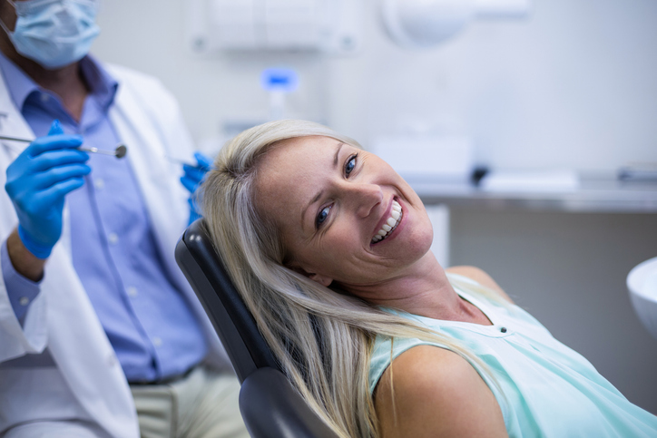 paciente sentada en silla de dentista feliz con el resultado