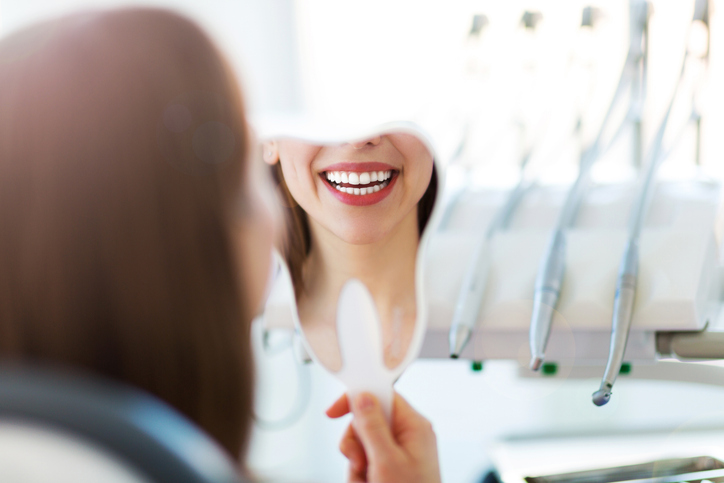 mujer en el dentista con espejo sonriendo