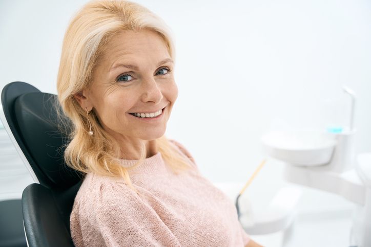 mujer en silla de clinica dental con implantes dentales