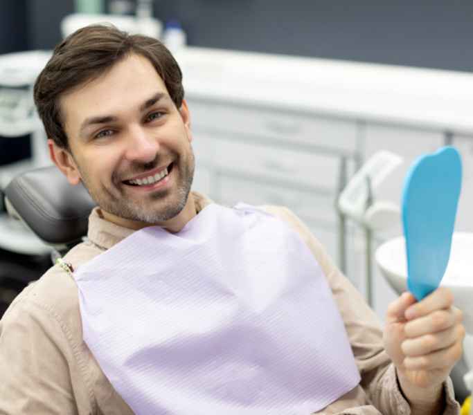 hombre sonríe porque le trataron la periodoncia